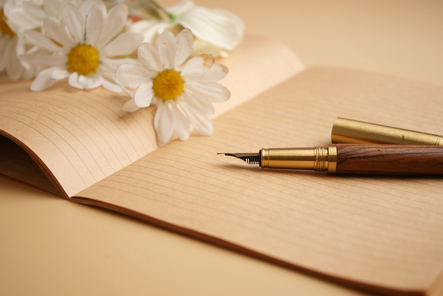 Writing with a fountain pen near flowers on a notebook