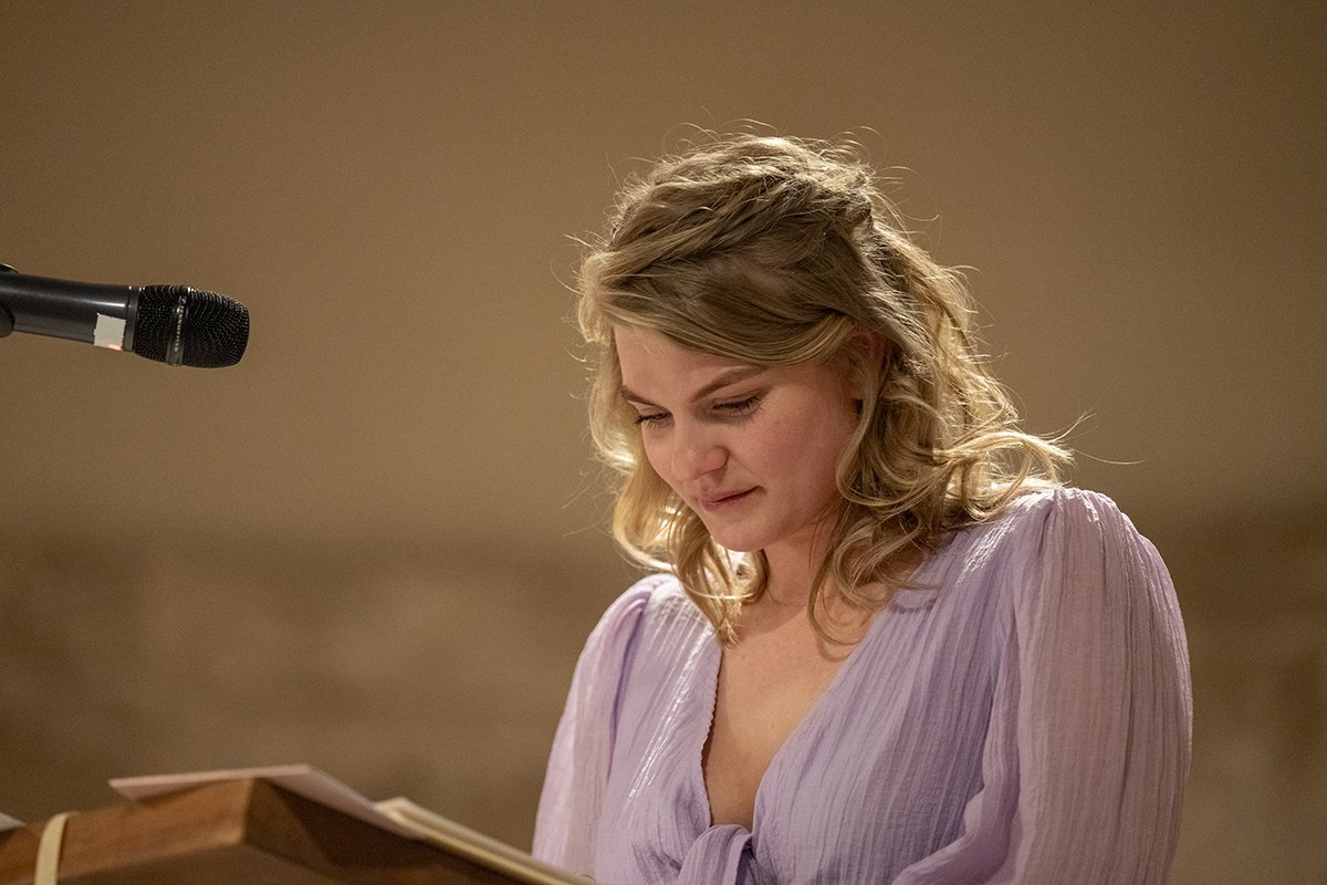 Woman giving a speech at a podium with a microphone in a warmly